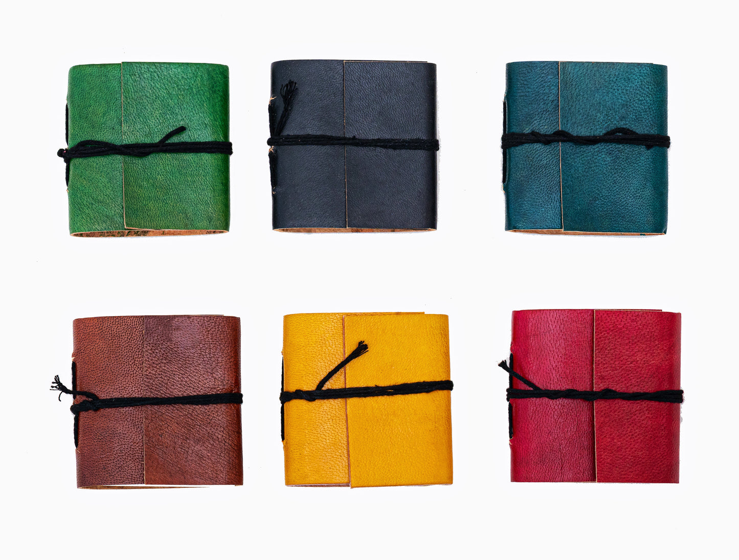 Mini carnets artisanaux en cuir coloré avec fermeture par cordon noir, couleurs aléatoires sur fond blanc
