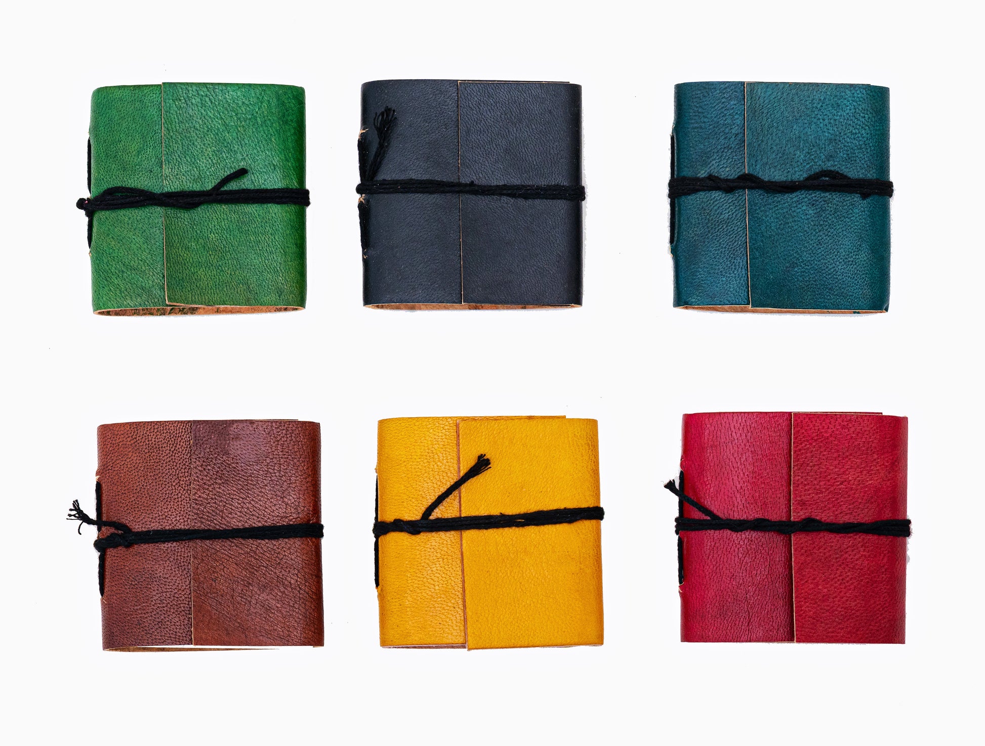 Mini carnets artisanaux en cuir coloré avec fermeture par cordon noir, couleurs aléatoires sur fond blanc