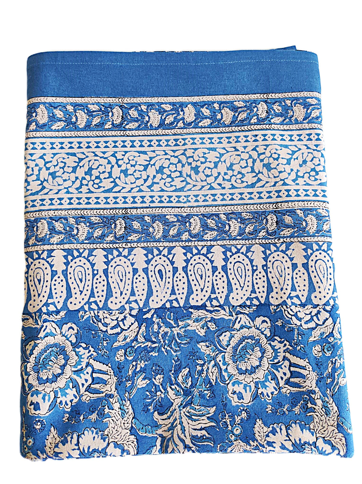 Nappe rectangulaire 6 places en coton Block Print indien bleu et écru, motifs floraux et cachemire, présentée pliée et dressée sur une table extérieure.
