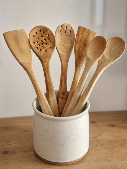 Set de 6 ustensiles de cuisine artisanaux en bois de Neem naturel avec cuillères, spatules, fourchette et écumoire sur fond blanc.
