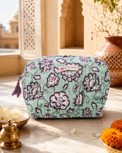 Trousse de toilette matelassée vert d’eau From India Boutique, en coton imprimé floral violet et blanc, présentée dans une ambiance lumineuse inspirée de l’Inde avec décor artisanal et fleurs.
